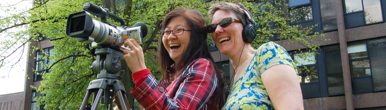 Two women laughing while filming with a video camera